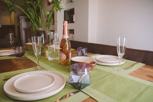 Luxury Table Runner Green - Organic Cotton & Handmade displayed on a dining table with plates and glasses.
