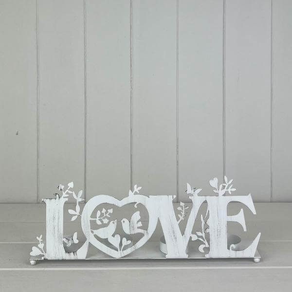 LOVE Tealight Holder 31cm displayed on a shelf, featuring intricate floral designs and a heart shape.
