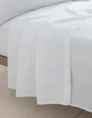 Luxury Flat Sheet - Organic Cotton draped elegantly over a bed in a serene bedroom setting.