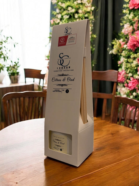 Citrus & Oud Reed Diffuser 100ml displayed on a wooden table with floral backdrop.