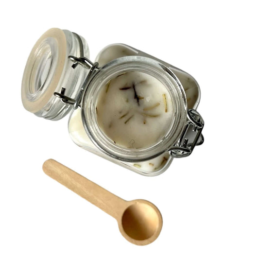 Cozumel Scoopable Wax Melt in a glass jar with a wooden scoop, featuring floral and tropical scents.