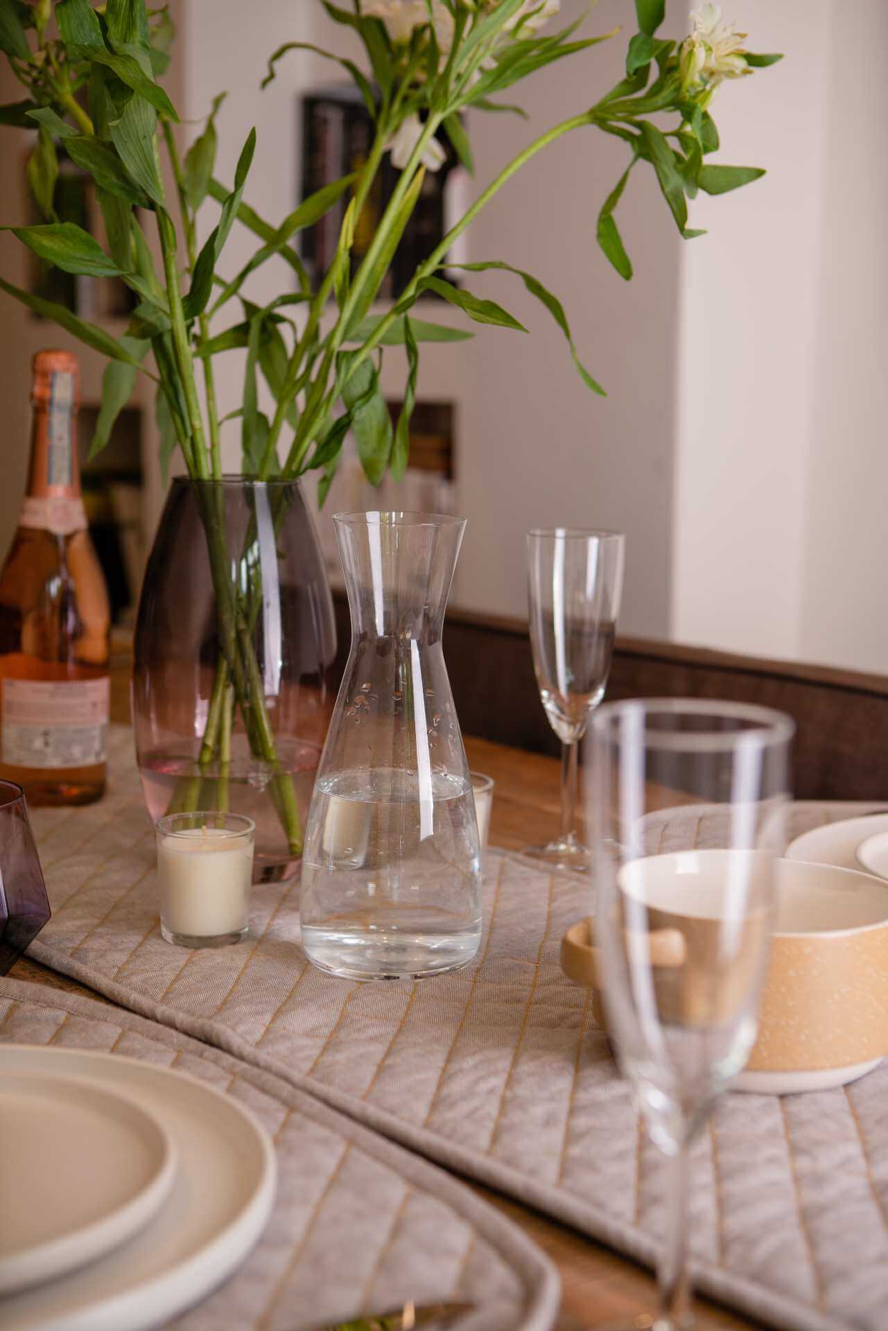 Table setting featuring a Quilted Table Runner - Organic Cotton, elegant glassware, and floral centerpiece.