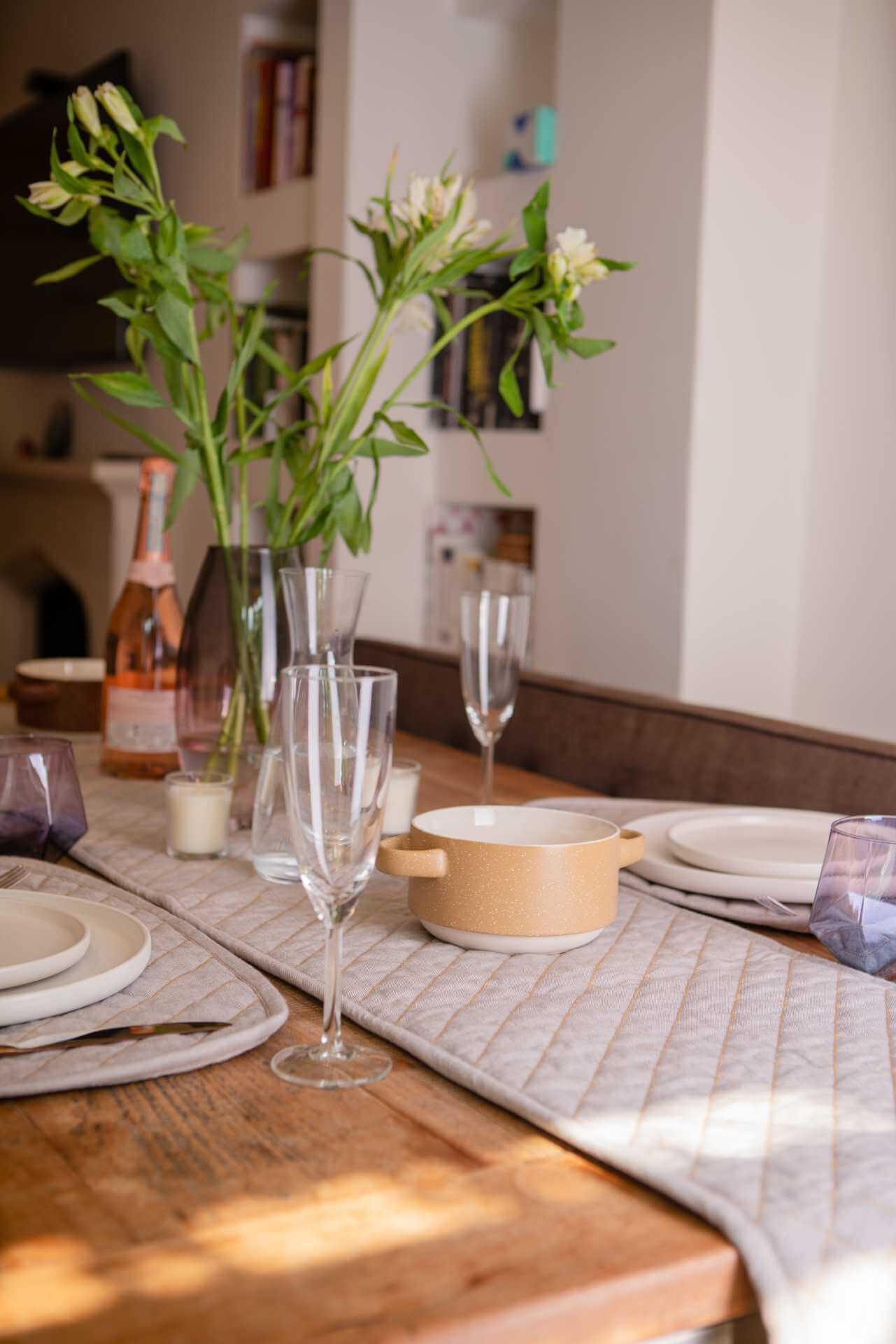 Quilted Table Runner - Organic Cotton set on a dining table with plates, glasses, and flowers, styled for an elegant meal.