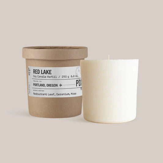 Red Lake Scented Candle Refill in a rustic container next to a white candle, evoking Oregon's forest scents.
