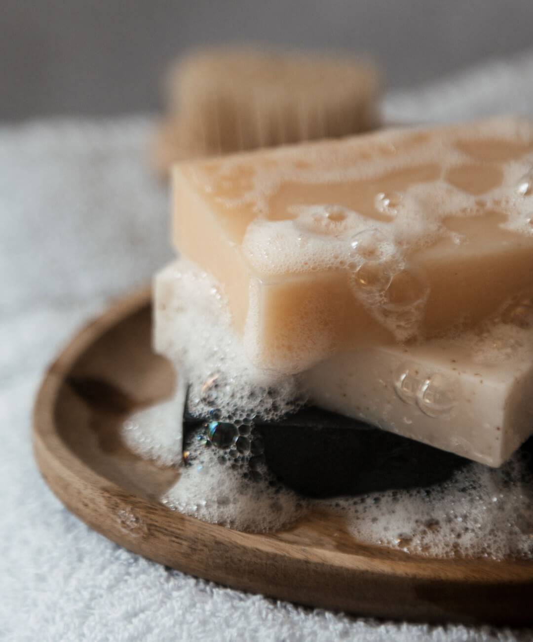 Natural Soap Bar Bundle 5 pack displayed on a wooden plate with bubbles and foam, emphasizing natural ingredients.
