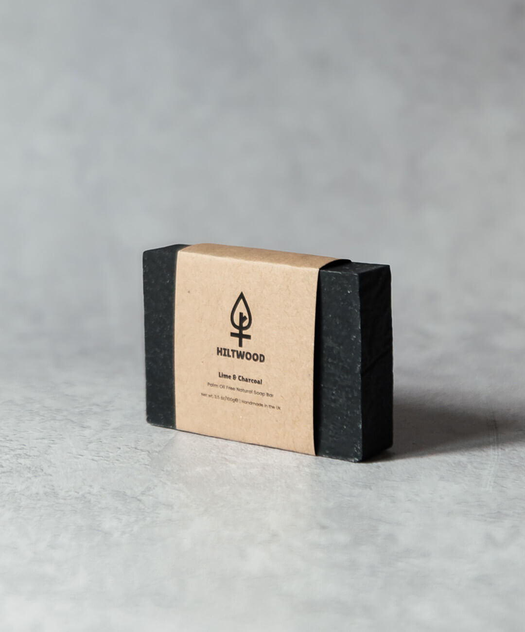 Lime & Charcoal Natural Soap Bar with natural packaging on a textured surface.