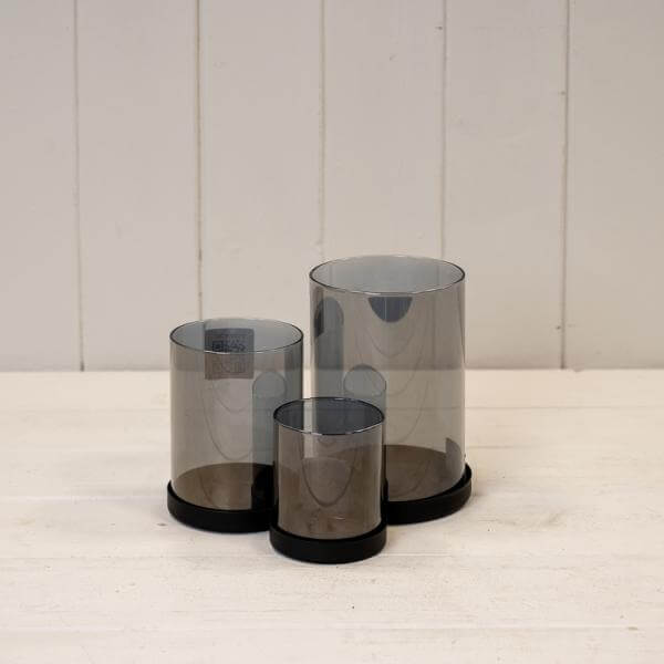 Set of Three Black Glass Candle Holders with Metal Base arranged on a wooden surface.
