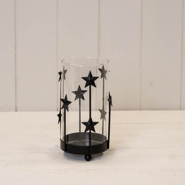 Small Black Metal Star Candle Holder with Glass Insert displayed on a white wooden surface.