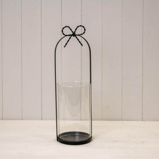 Large Black Metal Candle Holder with Bow displayed on a wooden surface, showcasing its elegant design.