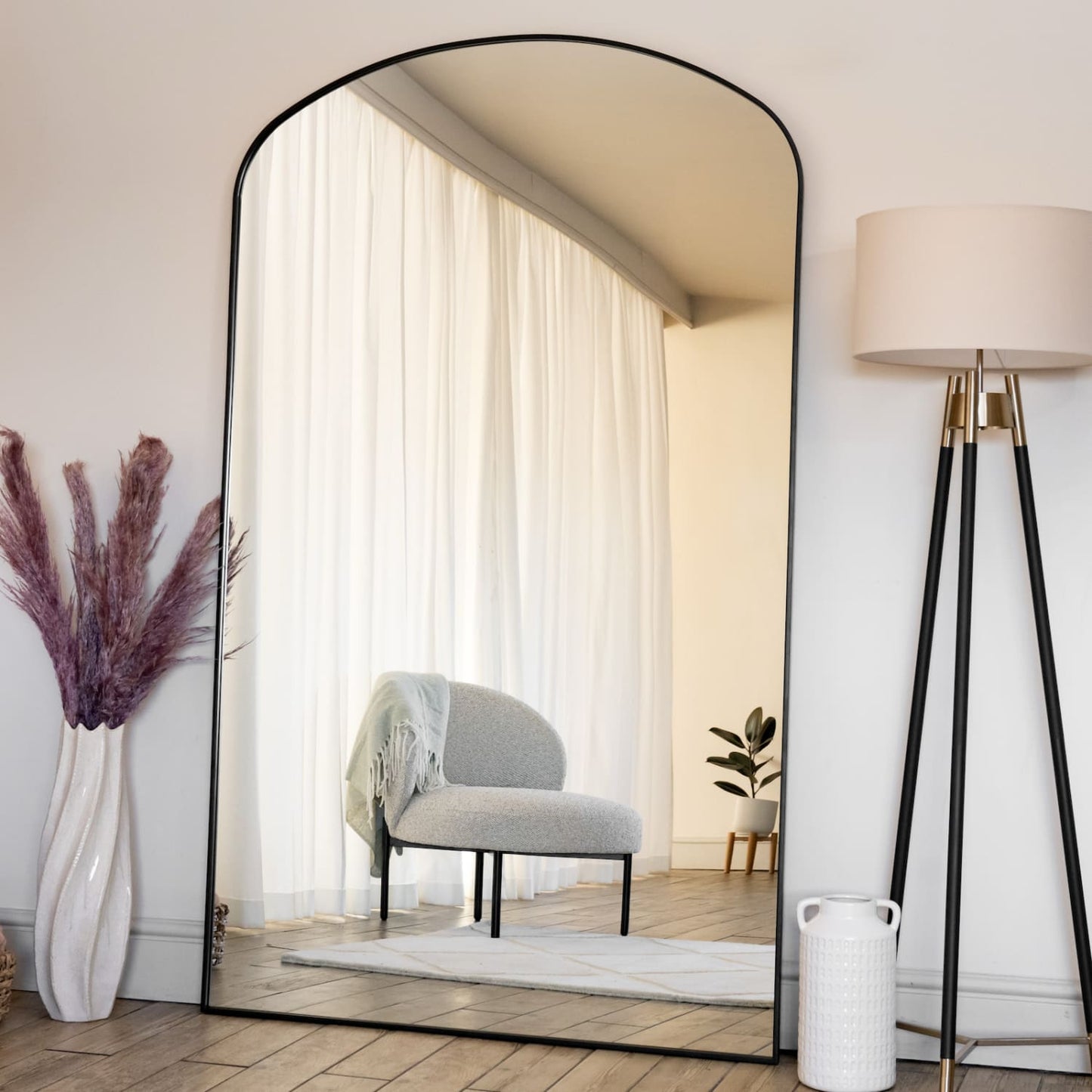 Yoko - Black Metal Gentle Arch Mirror - 180cm x 105cm reflecting a modern living space with soft furnishings.